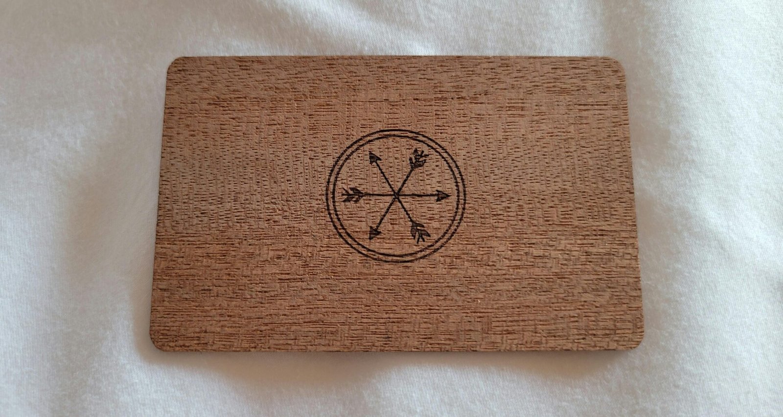 Nahaufnahme einer Visitenkarte aus Holz mit eingraviertem Kompass auf einer Tischoberfläche