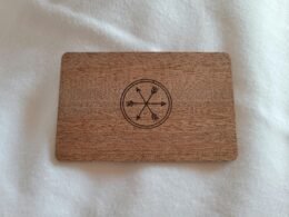 Nahaufnahme einer Visitenkarte aus Holz mit eingraviertem Kompass auf einer Tischoberfläche