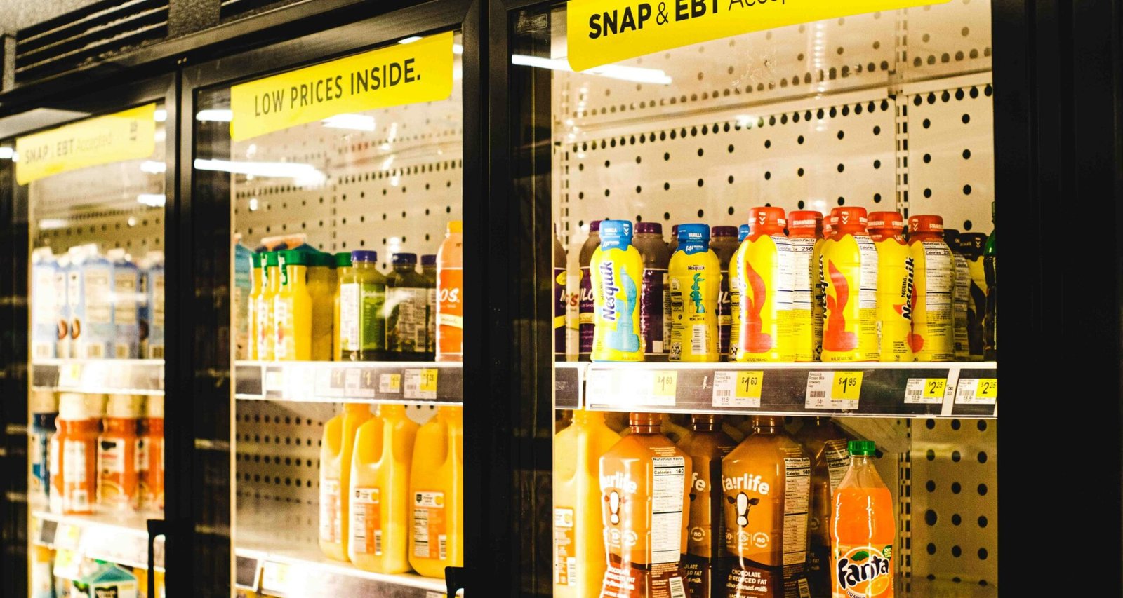 Ein Kühlregal in einem Supermarkt, das mit mehreren Flaschen Orangensaft sorgfältig bestückt ist.