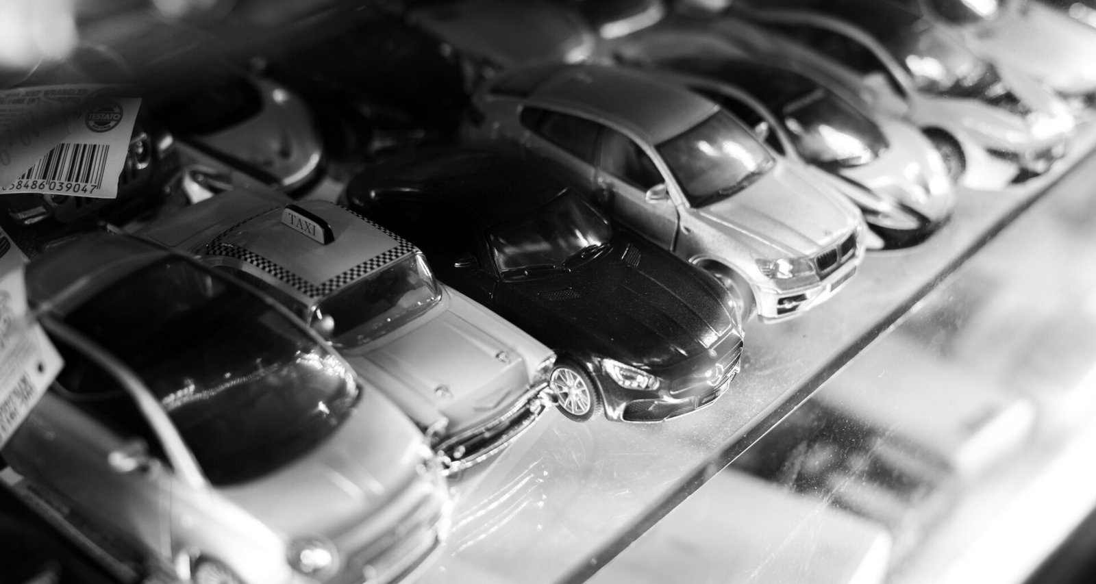Eine Vitrine voller verschiedener Spielzeugautos, ordentlich aufgereiht und von vorne fotografiert.