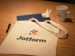 Weiße Tasche steht auf einem hellen Holztisch in moderner, minimalistischer Umgebung.