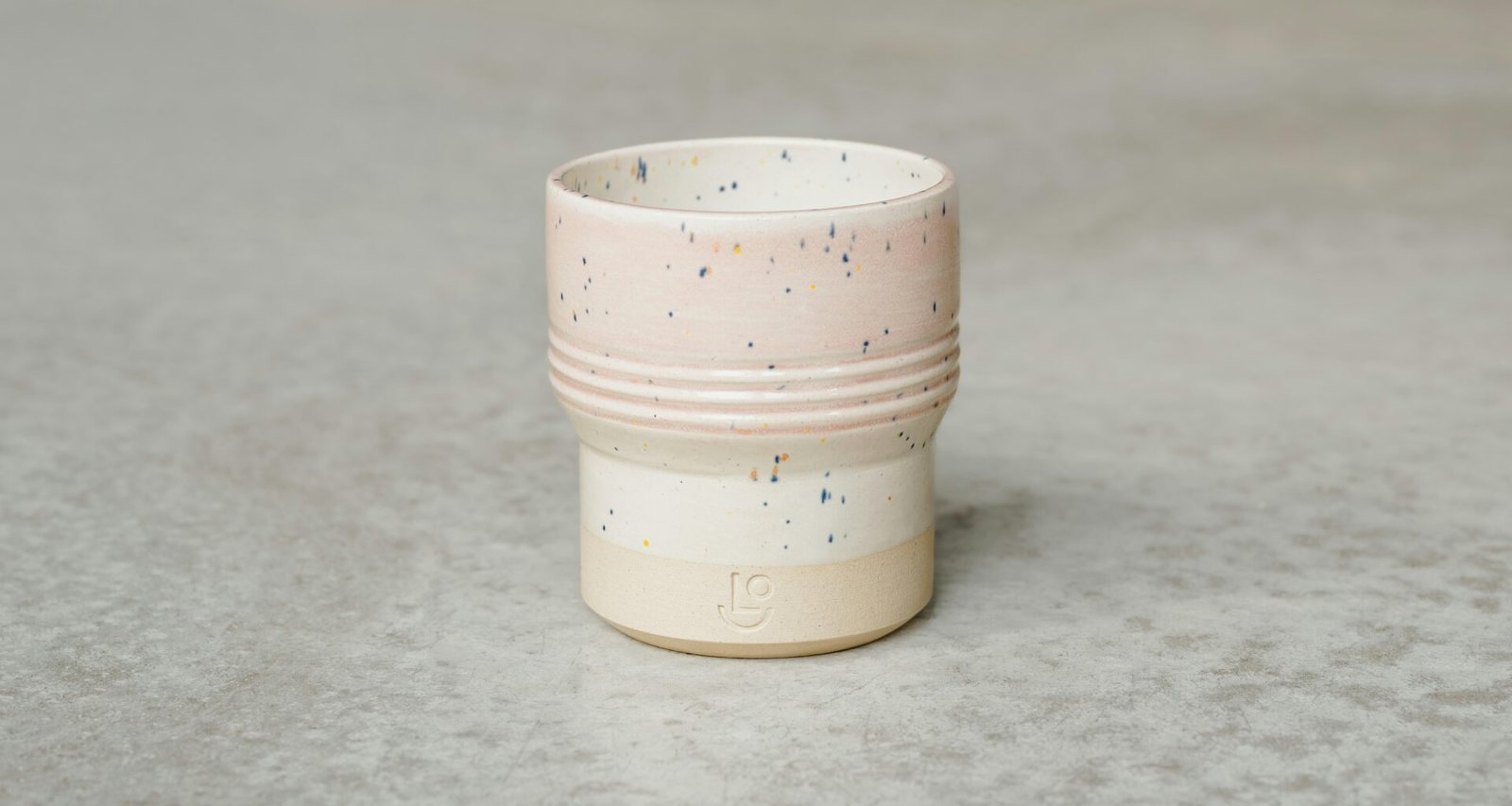 Weiße Kaffeetasse steht auf einer grauen Oberfläche in minimalistischem Stil, fotografiert bei natürlichem Licht.