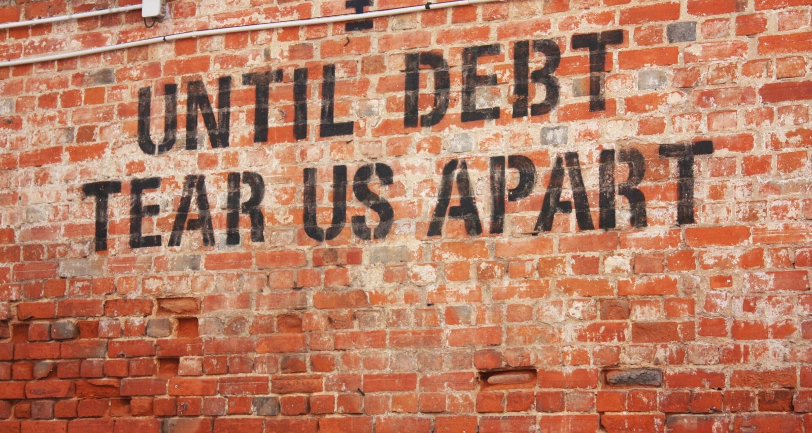 Ziegelwand mit aufgetragenem Schriftzug, der eine Botschaft vermittelt, Nahaufnahme in neutralem Licht.