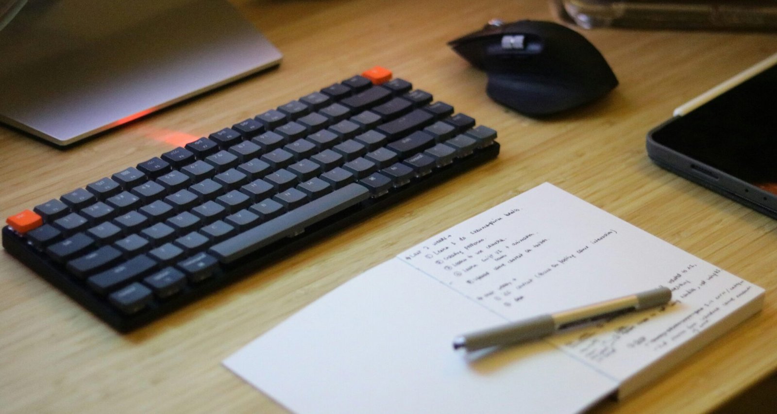 Schreibtisch mit Tastatur, Maus, Smartphone und Notizblock – ideale Ausstattung für produktives Arbeiten im Büro oder Homeoffice.
