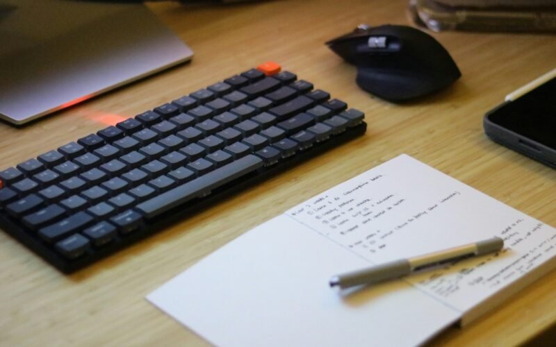 Schreibtisch mit Tastatur, Maus, Smartphone und Notizblock – ideale Ausstattung für produktives Arbeiten im Büro oder Homeoffice.