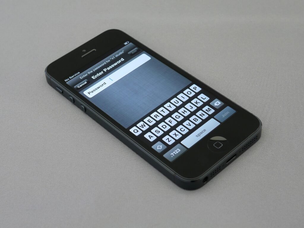 Eingeschaltetes iPhone 5 mit sichtbarem Homescreen und Apps auf hellem Hintergrund abgebildet