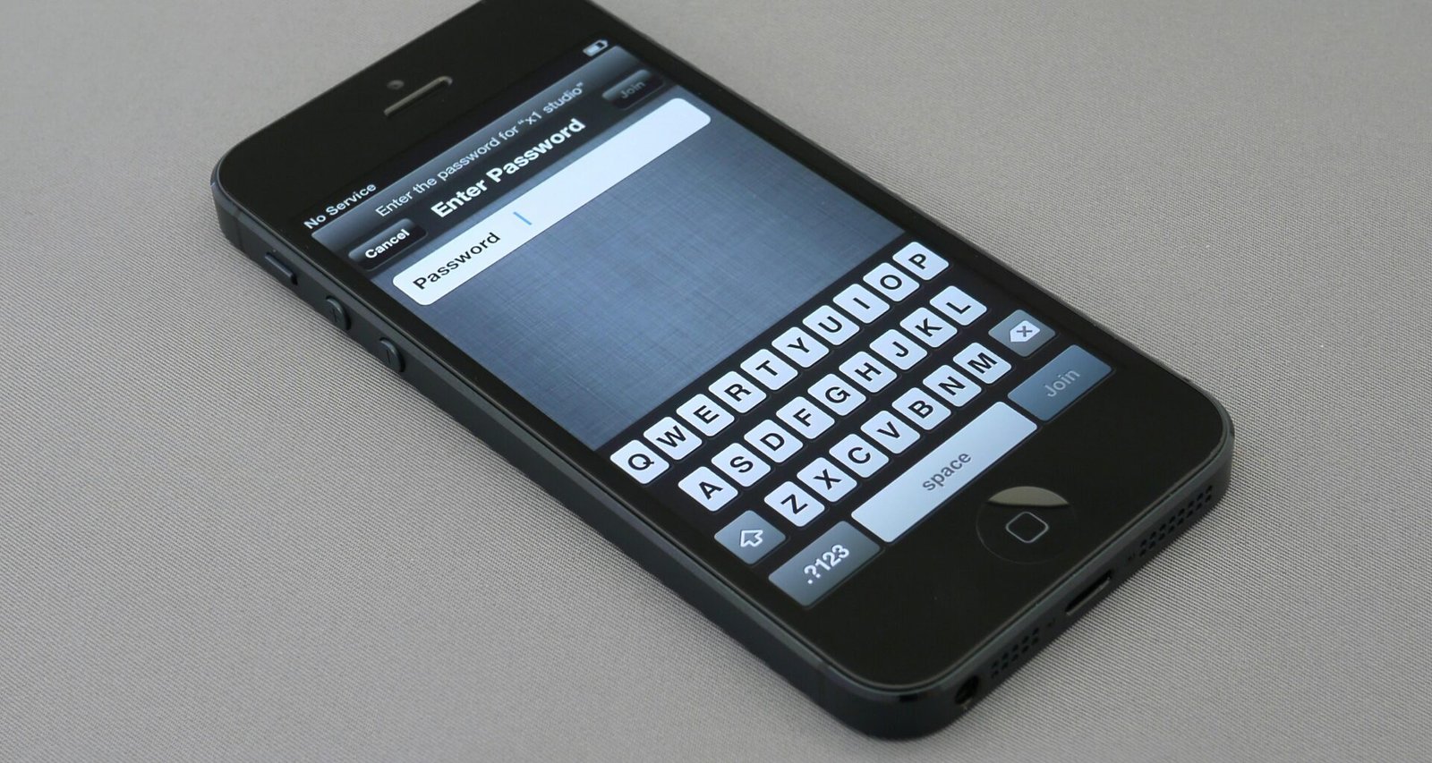 Eingeschaltetes iPhone 5 auf einer Oberfläche, Display zeigt den Homescreen, modernes Smartphone-Design im Detail dargestellt