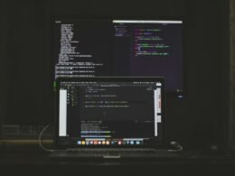 Ein eingeschaltetes MacBook Pro mit leuchtender Tastatur steht auf einem Tisch in moderner Umgebung