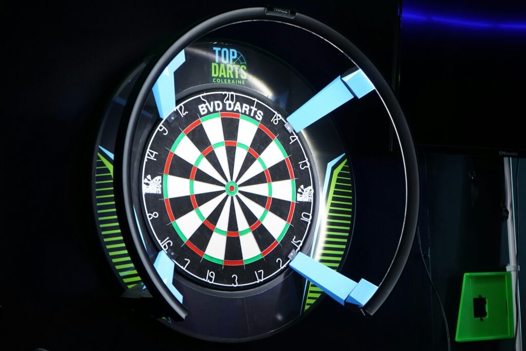 Elektronische Dartscheibe mit illuminierter Umrandung in dunkler Umgebung, leuchtet mit bunten LEDs.