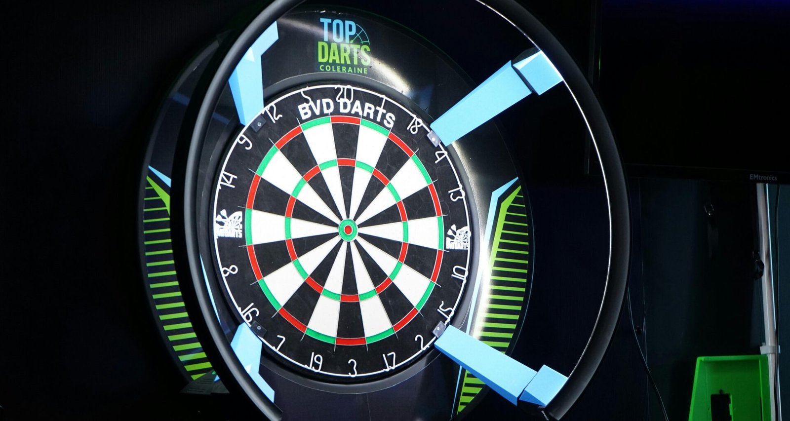 Elektronische Dartscheibe mit illuminierter Umrandung in dunkler Umgebung, leuchtet mit bunten LEDs.