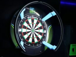 Elektronische Dartscheibe mit illuminierter Umrandung in dunkler Umgebung, leuchtet mit bunten LEDs.