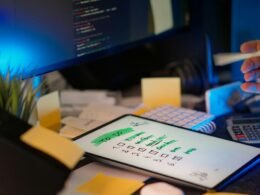 Entwickler sitzt in einem abgedunkelten Büro und arbeitet an mehreren Computerbildschirmen