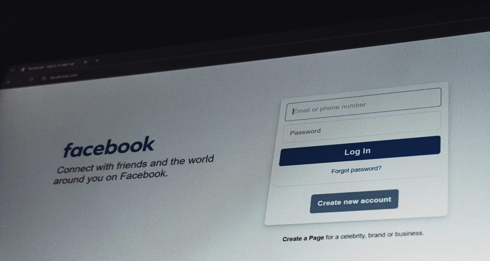 Facebook-Login-Bildschirm auf einem Computer-Monitor mit blauem Hintergrund, Eingabefeldern und Login-Button im Fokus