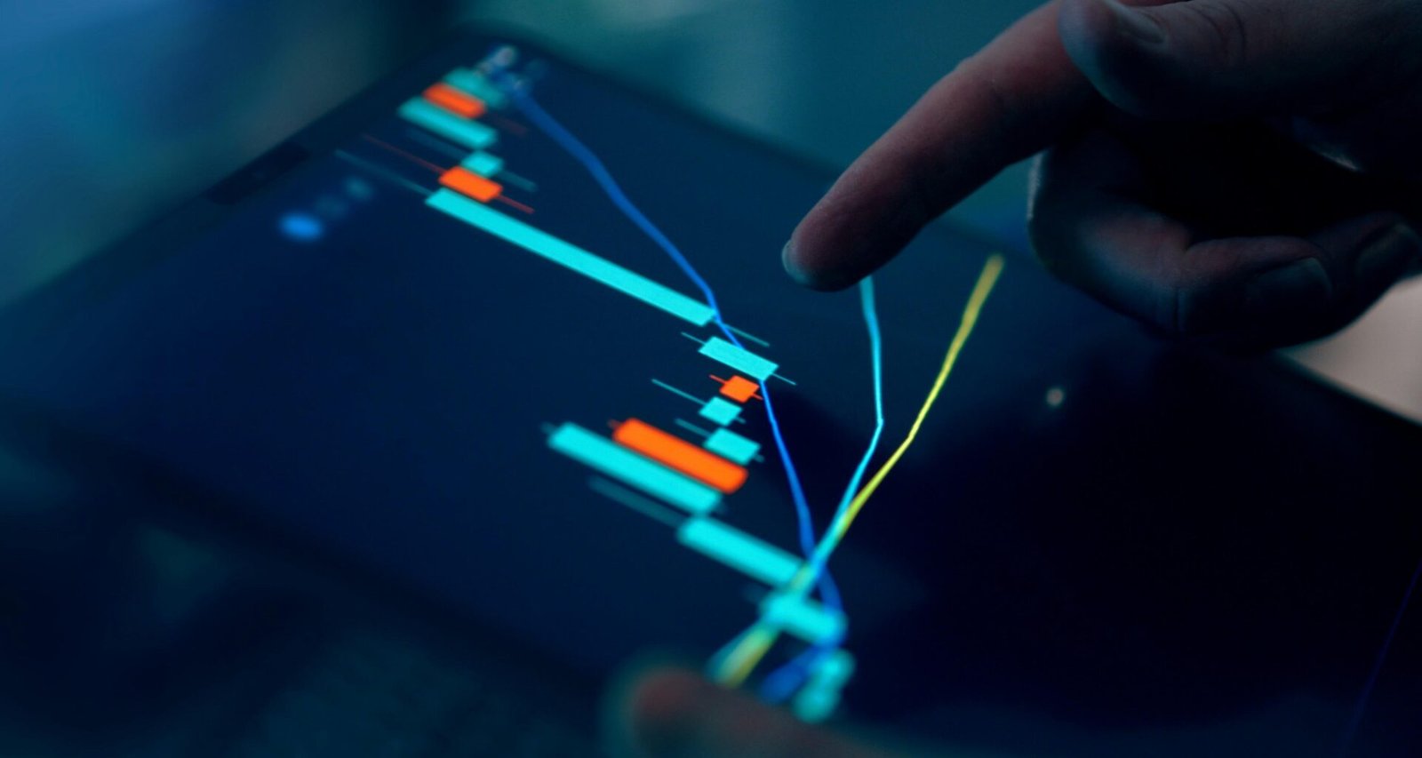 Hand tippt auf Tablet, das einen Börsengraphen anzeigt, Symbol für digitale Finanzanalyse und moderne Technologie
