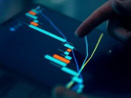 Hand tippt auf Tablet, das einen Börsengraphen anzeigt, Symbol für digitale Finanzanalyse und moderne Technologie