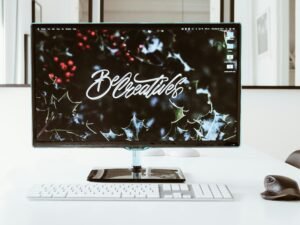 Flachbildschirm-Computer eingeschaltet auf Schreibtisch, moderner Arbeitsplatz, Fokus auf Technik und Digitalisierung