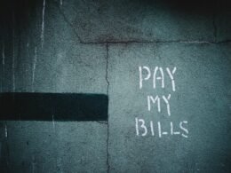 Schriftzug „Pay My Bills“ als Graffiti auf einer Wand, unscharf fotografiert und als Symbol urbaner Street-Art dargestellt