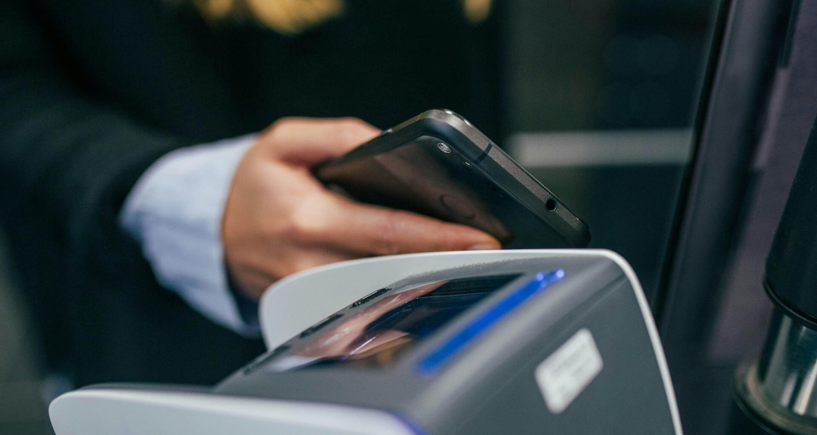 Eine Hand hält ein Smartphone, Aufnahme in geringer Schärfentiefe mit Fokus auf das Gerät