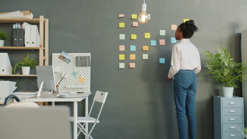 Frau ordnet farbige Haftnotizen an einer Wand während einer Team-Brainstorming-Session im Büro
