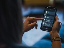 Frau nutzt ihr Smartphone, um Geräte im Smart Home per App zu steuern; modernes vernetztes Wohnen sichtbar