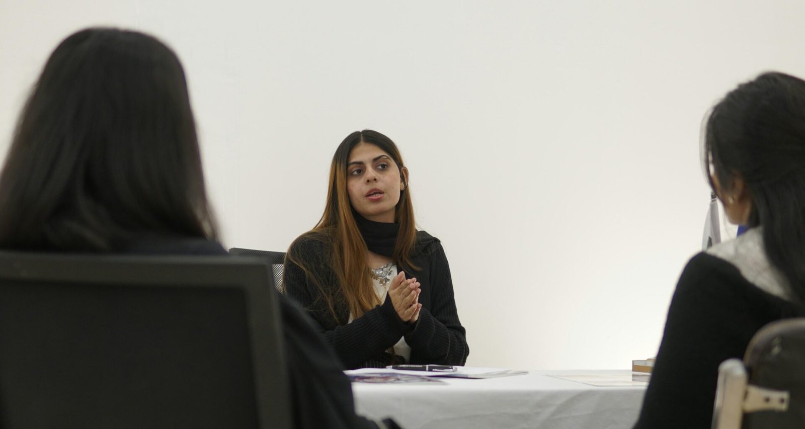 Eine Frau sitzt mit zwei Personen an einem Tisch und spricht mit ihnen während eines Geschäftstreffens im Büro.