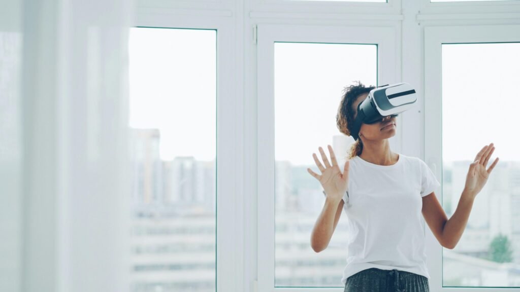 Frau mit Virtual-Reality-Headset sitzt im Innenraum nahe eines großen Fensters und testet moderne Technologie.