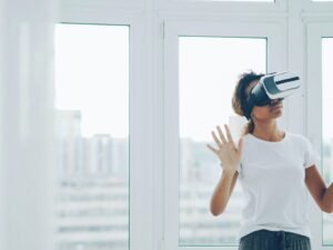 Frau mit Virtual-Reality-Headset sitzt im Innenraum nahe eines großen Fensters und testet moderne Technologie.