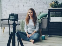Frau filmt sich mit einer Kamera in einem gut beleuchteten Raum, ideal für Homeoffice- oder Vlogging-Artikel