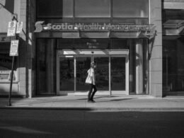 Eine Frau geht am Eingang von Scotia Wealth Management vorbei, Glasfassade und Firmenlogo sind sichtbar.