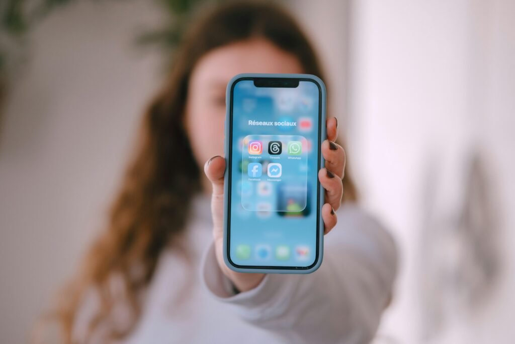 Frau hält ein Smartphone in der Hand, auf dem zahlreiche App-Icons deutlich auf dem Bildschirm dargestellt sind.