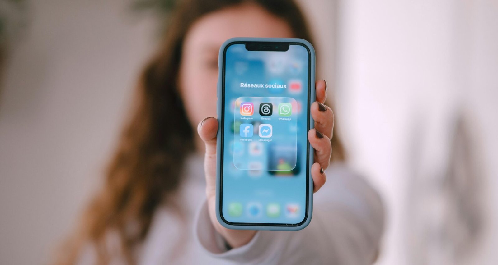 Frau hält Smartphone mit sichtbaren App-Icons auf dem Display, Fokus auf moderner mobiler Nutzung und digitale Anwendungen
