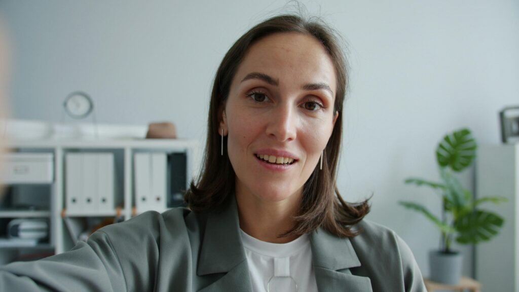 Frau im eleganten Anzug sitzt und schaut direkt in die Kamera, professionelle Business-Atmosphäre