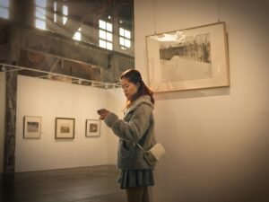 Frau mit grauem Mantel steht vor einer weißen Wand, schlichtes und modernes Motiv für Lifestyle- oder Mode-Artikel