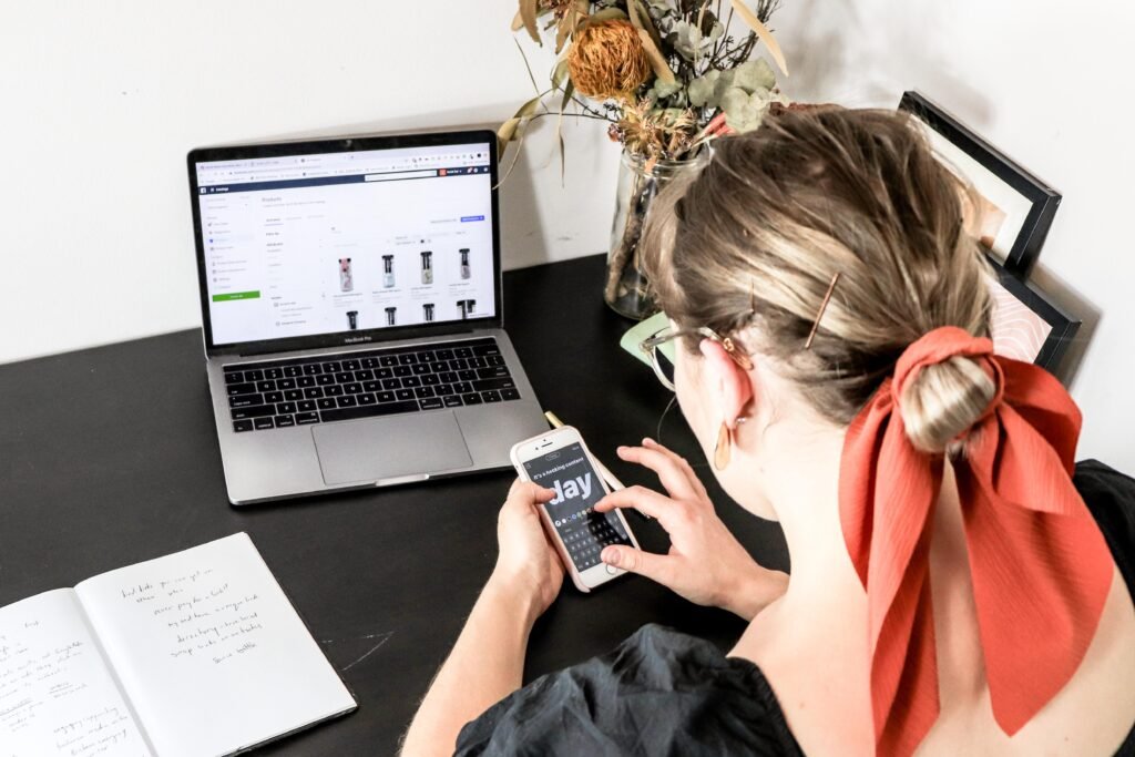 Frau im orangefarbenen Shirt hält ein iPhone in den Händen und nutzt das Smartphone im Alltag
