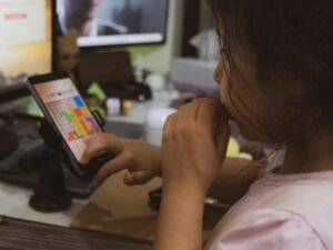 Frau im pinken Shirt hält ein Smartphone in der Hand und nutzt es, Fokus auf mobile Kommunikation im Alltag