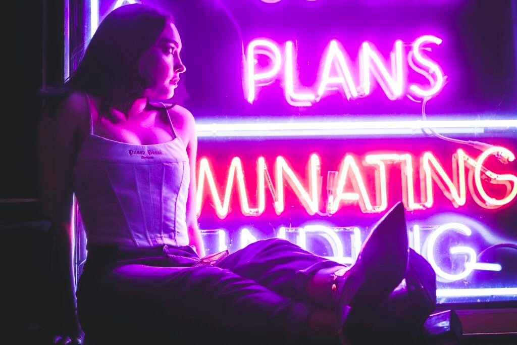 Frau mit weißem langen Shirt sitzt auf dem Fußboden in einem hellen Raum, Blick nach vorne gerichtet