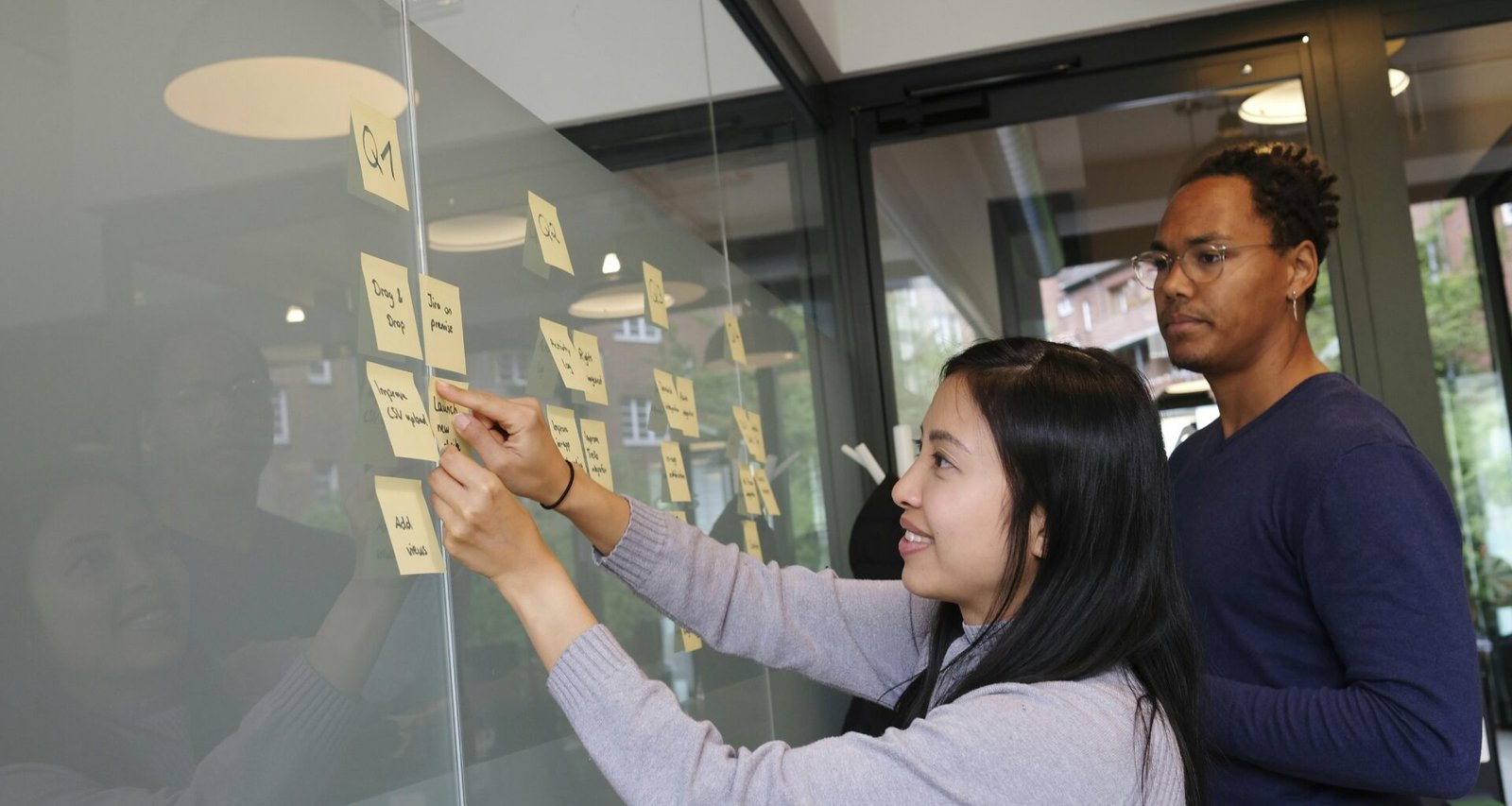 Frau in grauem Pullover hält ein goldenes iPhone 6 in der Hand und nutzt das Smartphone im Alltag.