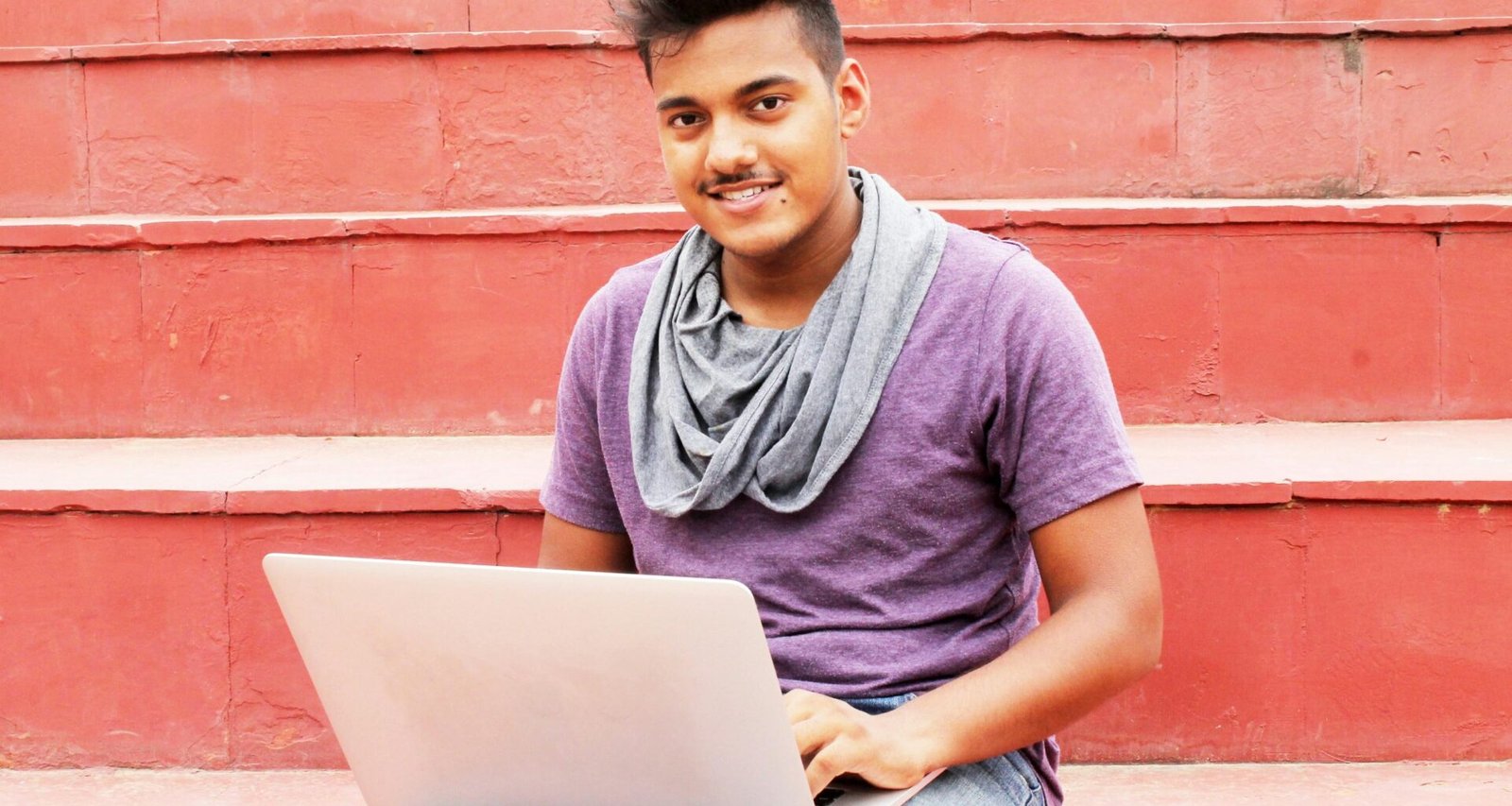 Frau im lila Shirt und blauer Jeans sitzt auf einer Betonbank, Alltagsszene in einer urbanen Umgebung