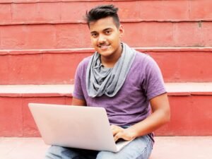 Frau im lila Shirt und blauer Jeans sitzt auf einer Betonbank, Alltagsszene in einer urbanen Umgebung