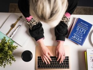Frau mit schwarzem und pinkem Langarmshirt arbeitet an einem MacBook Pro an einem Schreibtisch in moderner Umgebung.