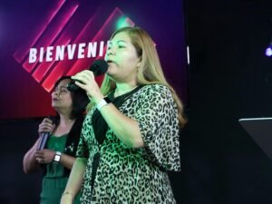 Frau in schwarz-weißem Leopardenkleid singt auf einer Bühne mit Mikrofon und Bühnenbeleuchtung