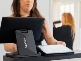 Frau arbeitet mit einem Tablet an einer Kasse in einem Geschäft, modernes Bezahlsystem im Einzelhandel sichtbar