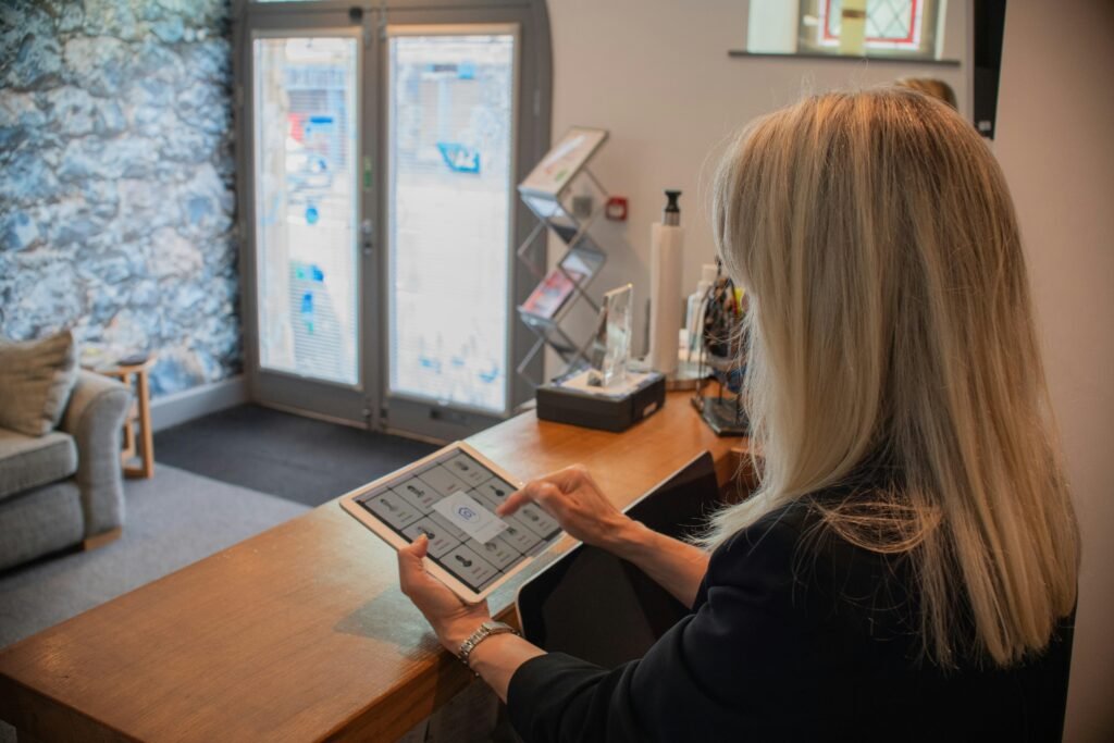 Eine Frau bedient ein Tablet an einem modernen Empfangstresen im Büro. Fokus auf Digitalisierung und Organisation.