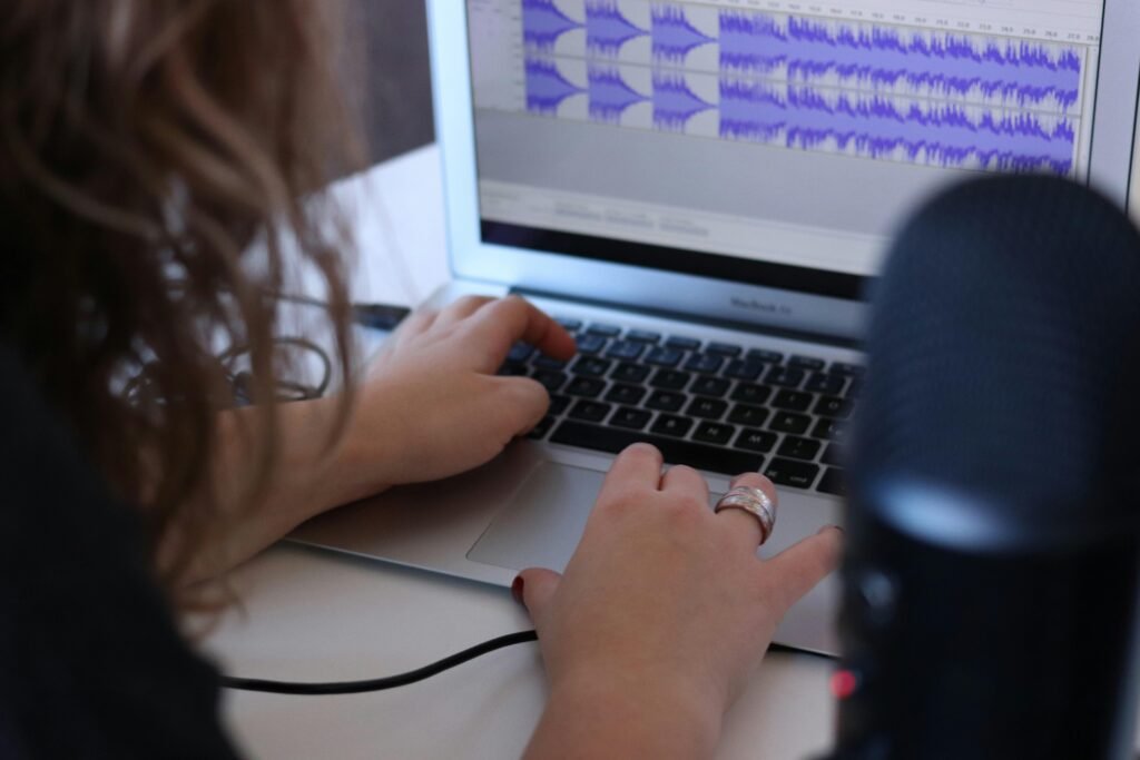 Frau sitzt mit einem MacBook Air an einem Tisch in einem hellen Raum und arbeitet konzentriert am Laptop.