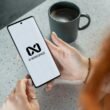 Frau hält ein Smartphone mit sichtbarem AI Workspace Logo, Symbol für digitale Arbeitsmethoden und künstliche Intelligenz