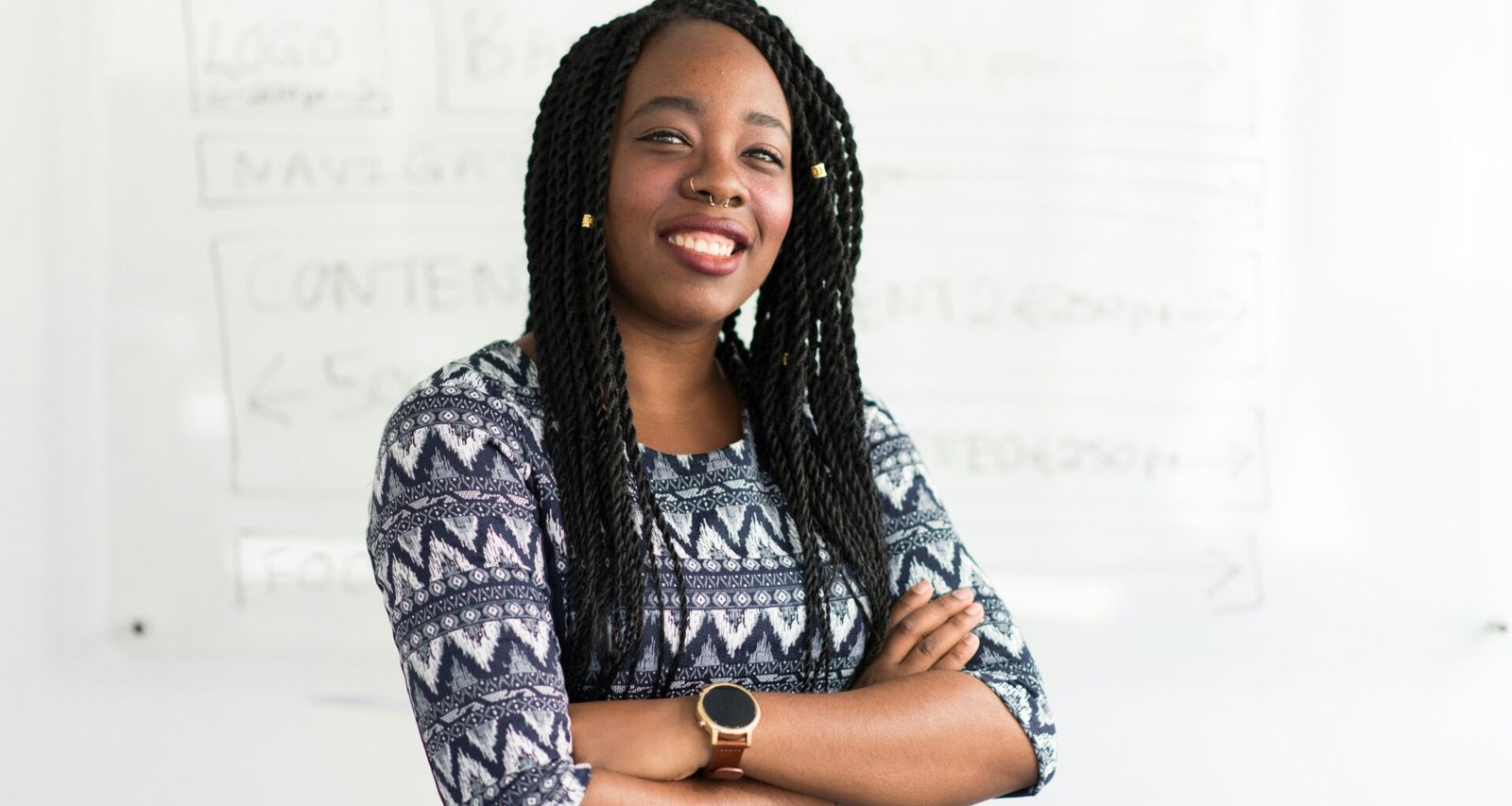 Lächelnde Frau mit verschränkten Armen, geeignet für Artikel über Arbeitswelt, Diversität oder Karriere im digitalen Umfeld