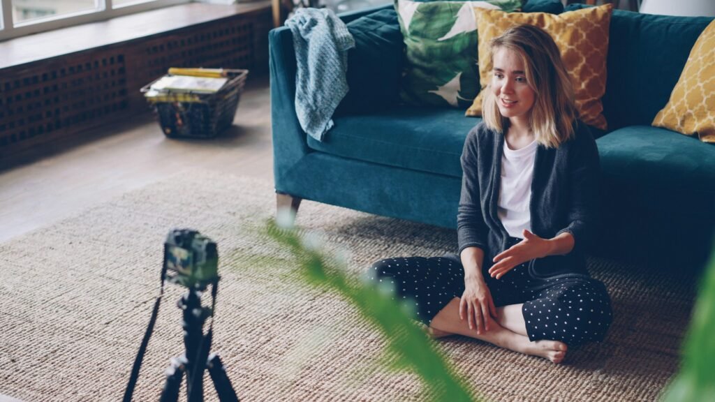 Frau sitzt auf dem Fußboden und filmt sich selbst mit einer Kamera für Social-Media-Beiträge