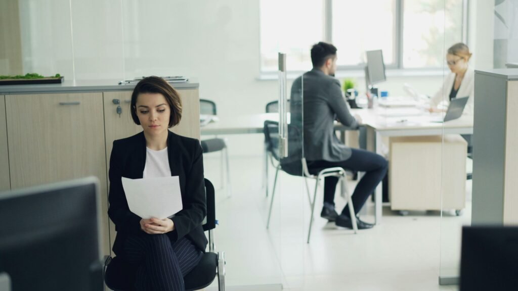 Eine Frau sitzt an einem modernen Büroschreibtisch und hält mehrere Papierdokumente in den Händen