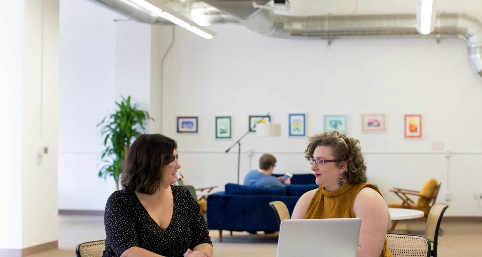 Mehrere Frauen sitzen zusammen an einem Tisch und führen ein Gespräch in einem modernen Büro oder Konferenzraum.