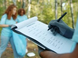 Zwei Freiwillige prüfen ein Klemmbrett während einer koordinierten Aufräumaktion im Freien